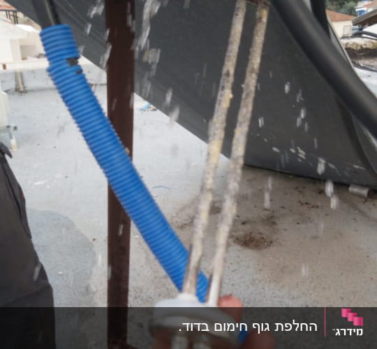 יד מחזיקה גוף חימום של דוד שמש עם מים זורמים